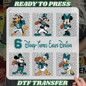 May include: A DTF transfer sheet featuring six Disney-themed Eagles designs. The designs include cartoon characters like Goofy, Mickey, and Minnie Mouse, each wearing Eagles football uniforms and holding a football. The sheet includes the text "READY TO PRESS" and "DTF TRANSFER".