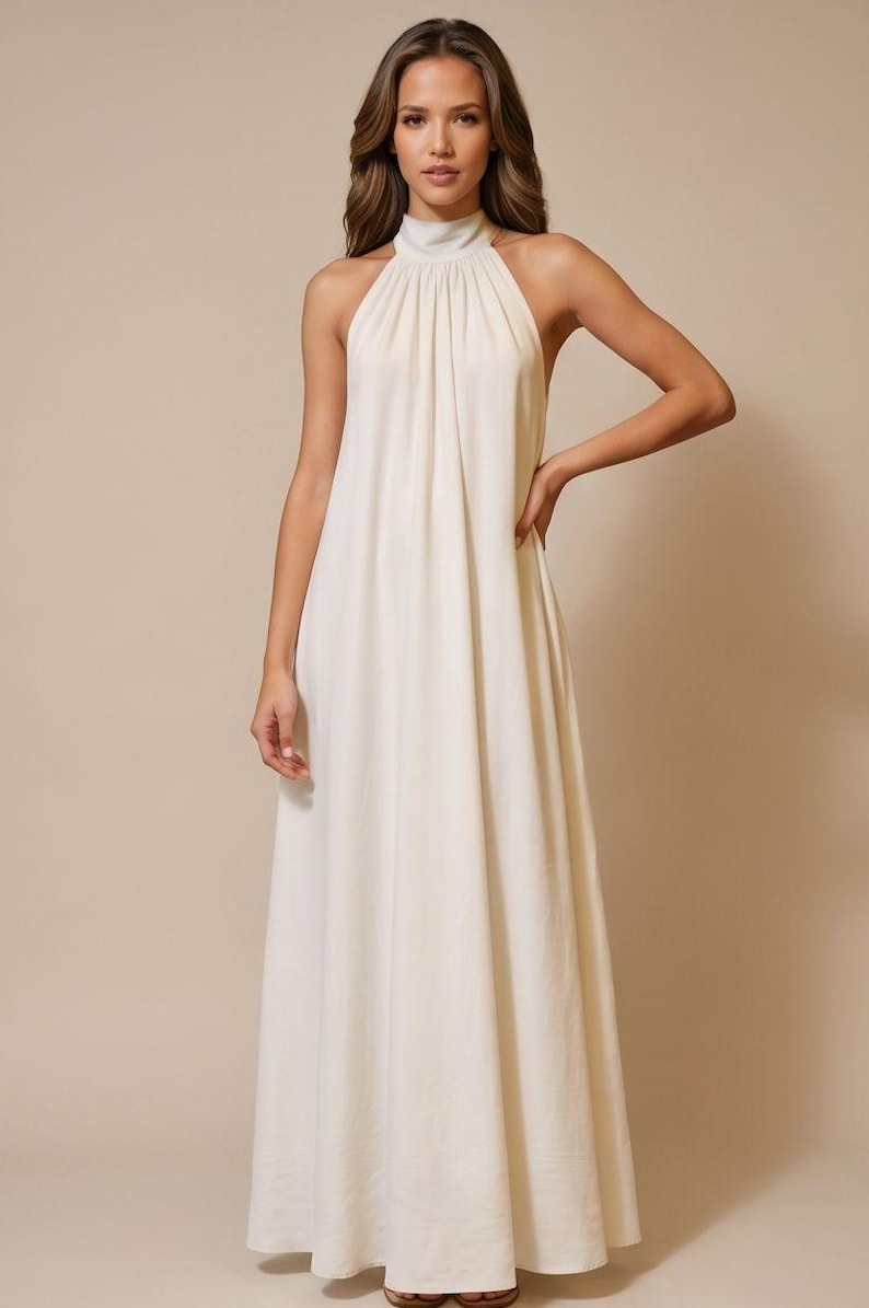 May include: A floor-length, ivory-colored dress with a halter neckline. The dress features a high, gathered neckline and a flowing, A-line skirt. The fabric appears to be a lightweight material, suitable for warmer weather. The dress is a solid color.