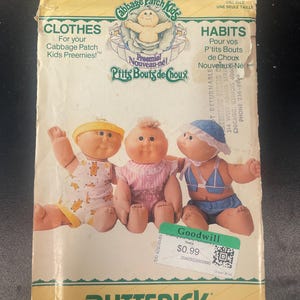 May include: A Butterick sewing pattern envelope number 4923 for Cabbage Patch Kids Preemies clothes. The packaging features three dolls wearing different outfits, including a yellow hat, a pink dress, and a blue sun hat with a matching two-piece set.