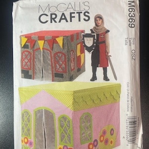 May include: McCall's Crafts sewing pattern M6369 featuring a child's knight costume and two playhouse designs. The playhouses are decorated with colorful fabric and trim. The knight costume includes a tunic, hood, shield, and sword.
