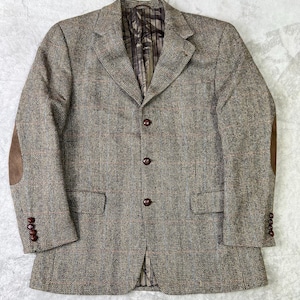 May include: A brown tweed blazer with elbow patches and a three-button closure. The jacket has a classic design with a notched lapel and two front pockets. The buttons are a dark brown color.