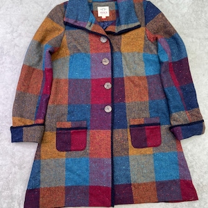 May include: A long-sleeved coat featuring a multi-colored herringbone plaid pattern in shades of blue, red, orange, and purple. The coat has a fold-over collar, four front buttons, and two patch pockets. The interior label reads AVOCA.