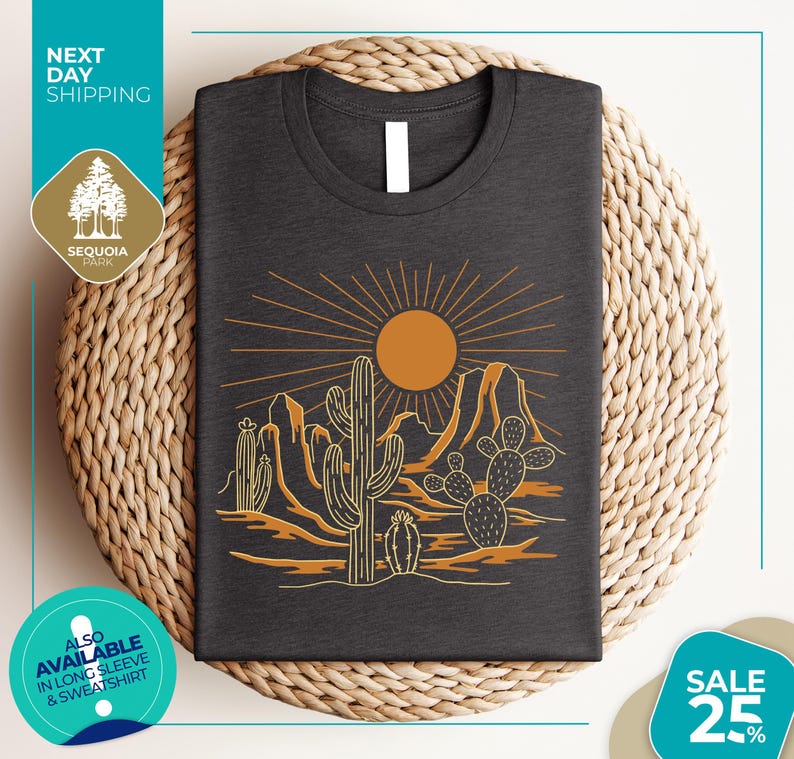 a gray t-shirt with a desert landscape design, including cacti and mountains, along with a sun and rays. The t-shirt is displayed on a woven basket, and there are various texts and logos surrounding the image.