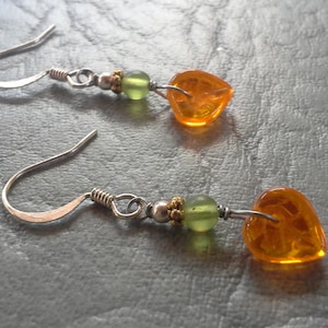 May include: A pair of silver earrings with orange and green glass heart-shaped beads.