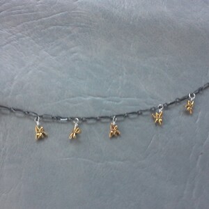 May include: A silver chain bracelet with gold butterfly charms hanging from it.