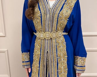 May include: A long, royal blue dress with intricate gold embroidery along the neckline, sleeves, and front. The dress features a matching gold belt with square embellishments. The sleeves are long and flowing, and the dress appears to be made of a soft fabric.