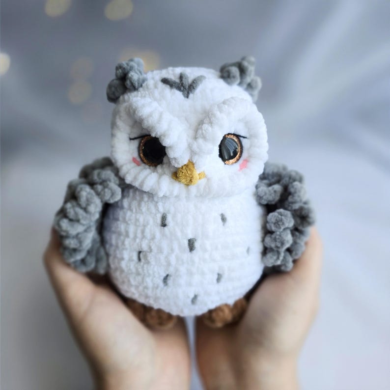 Pu&ograve; includere: Un gufo all'uncinetto bianco e grigio fatto a mano con occhi marroni, becco giallo e guance rosa. Il gufo ha ali e ciuffi grigi. &Egrave; un giocattolo morbido e di peluche.