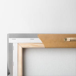 May include: Rear view of a stretched canvas art print. The canvas is wrapped around a wooden frame and stapled to the back. A brown paper backing is partially torn, revealing the frame. A metal sawtooth hanger is attached.