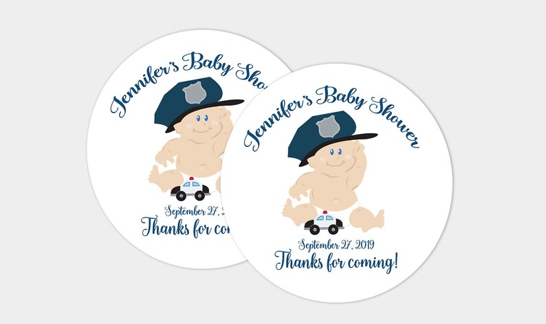May include: Two round white stickers with a cartoon baby wearing a blue police hat and holding a toy police car. The text on the stickers says "Jennifer's Baby Shower" and "September 27, 2019 Thanks for coming!"