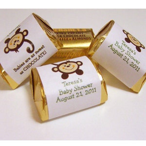 May include: Gold-wrapped chocolate bars with white labels featuring a cartoon monkey and the text "Babies are as sweet as CHOCOLATE!" and "Teresa's Baby Shower August 21, 2011".