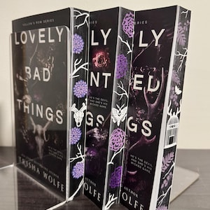 May include: A set of three paperback books with black covers and white text. The titles are "Lovely Bad Things", "Lovely Haunted Things", and "Lovely Wicked Things". The books are part of the "Hollow's Row" series and are written by Trisha Wolfe.