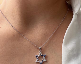 May include: A silver chain necklace with a pendant in the shape of a Star of David. The pendant is decorated with small blue and white stones.