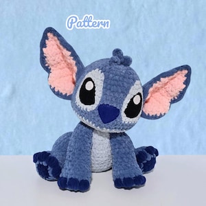 May include: A blue and light blue crocheted plush toy featuring large ears with pink inner sections, black and white eyes, and a dark blue nose. The word Pattern is printed in white text above the plush toy, which has a textured yarn finish.