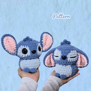 May include: Two handmade crochet plush toys featuring a blue and light blue character with large pink-lined ears. One plush has wide black eyes, while the other has closed eyes. The word Pattern is written in white script above the plush toys.