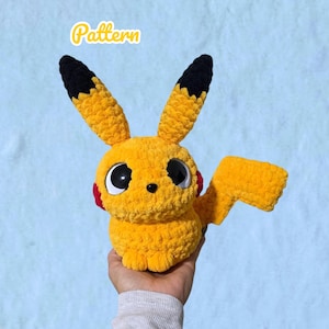 Op de afbeelding: Een geel gehaakt knuffeldier met lange oren met zwarte punten, grote zwarte ogen en rode ronde wangen. Het woord Pattern staat bovenaan in gele cursieve letters. De knuffel heeft een bliksemvormige staart en een zachte textuur.