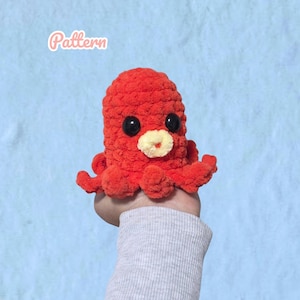 Op de afbeelding: Een felrood gehaakt octopus knuffeltje met grote zwarte plastic ogen en een klein crèmekleurig mondgedeelte. Het woord Pattern staat in witte cursieve letters in de linkerbovenhoek van de afbeelding. Het speelgoed heeft een textuur.