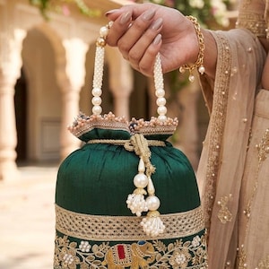 Könnte beinhalten: Eine dunkelgrüne, runde Handtasche mit Perlenhenkel und Quasten. Die Tasche hat goldene Stickereien mit einem Elefantenmotiv und Perlenverzierungen. Goldene Spitze säumt die oberen und unteren Kanten.