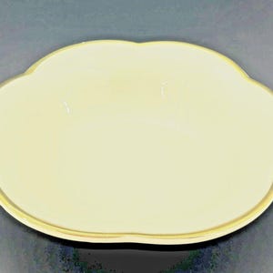 Puede incluir: Un plato de cerámica amarillo pálido con forma de nube y borde dorado. El plato tiene una superficie lisa y un borde festoneado. El plato es probablemente para servir comida o como objeto decorativo.