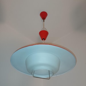 May include: A white and red ceiling light fixture with a saucer-shaped shade and a red cone-shaped top.