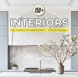 May include: A modern kitchen interior with white marble countertops and backsplash, gray cabinets, and a stainless steel stovetop. A vase with white blossoms sits on the counter.