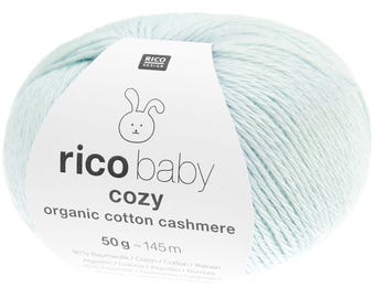 May include: A ball of light blue yarn with a label that reads "rico baby cozy organic cotton cashmere". The label features a bunny illustration and the text "50g ~ 145 m". The yarn is a soft, pastel color.
