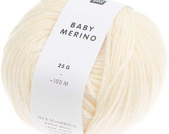 May include: A ball of cream-coloured Baby Merino yarn. A white label wraps around the yarn, displaying the text "BABY MERINO", "25 G", and "~100 M". The label also includes text in multiple languages, including "VIRGIN WOOL".