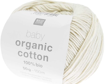 May include: A ball of cream-coloured baby organic cotton yarn. The label reads "RICO DESIGN" and "baby organic cotton 100% bio 50g - 150m". The yarn is tightly wound, showing the texture of the fibres.