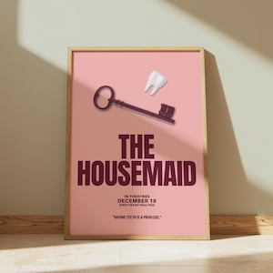 May include: A framed movie poster for "The Housemaid" with a pink background. The poster features a key and a tooth graphic. The title is in large, dark red letters, with the release date and director's name below.