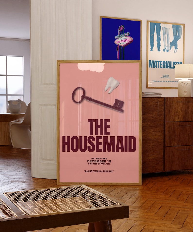 May include: A framed movie poster for "The Housemaid" with a pink background, a key, and a tooth graphic. The poster includes the text "In Theatres December 19" and "Having Teeth Is A Privilege."
