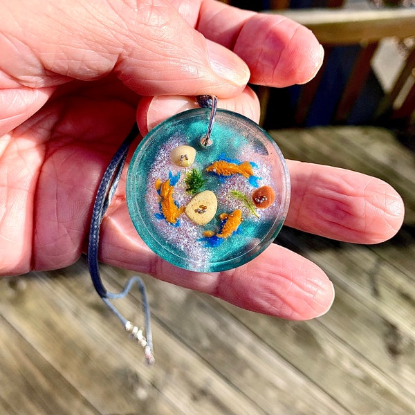 Diorama Necklace With 3 fish greenery and rocks.