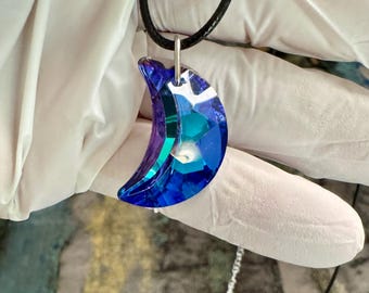Colgante de cristal facetado con forma de media luna azul y base plateada. 30 mm