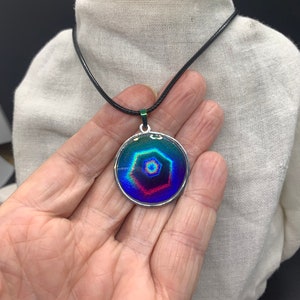 Holographic pendant with hexagon pattern shows multiple colors