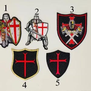 Peut inclure: Écussons brodés représentant des chevaliers médiévaux. Les écussons comprennent des images de chevaliers avec des épées et des boucliers, et des emblèmes de bouclier avec des croix rouges sur fond noir. Les écussons sont de différentes formes et tailles, avec des coutures détaillées et des couleurs vives.