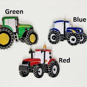 Può includere: Tre toppe ricamate a forma di trattore in verde, blu e rosso. Ogni trattore ha pneumatici neri con centri gialli. Le toppe sono etichettate con i colori: Verde, Blu e Rosso.