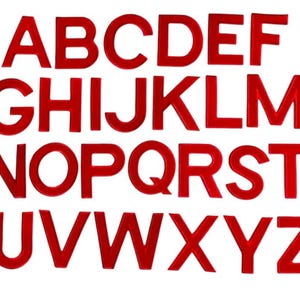 Può includere: Un set completo di lettere maiuscole rosse dell'alfabeto, disposte in righe e colonne su sfondo bianco. Le lettere sono di dimensioni uniformi e hanno una finitura lucida, adatte per lavori creativi o scopi educativi.