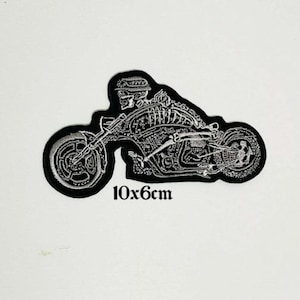May include: Black and white embroidered iron-on patch of a skeleton riding a motorcycle. The patch is 10x6cm.