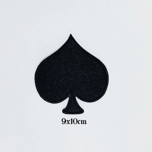 May include: A black spade patch, a playing card symbol, against a white background. The patch measures 3.5 x 4 inches. The patch is a solid black color and has a felt-like texture.