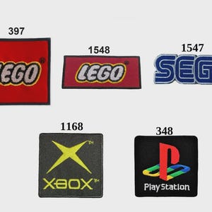 May include: Five embroidered patches featuring brand logos: a square red LEGO patch labeled 397, a rectangular red LEGO patch labeled 1548, a blue SEGA patch labeled 1547, a square black Xbox patch labeled 1168, and a square black PlayStation patch labeled 348.