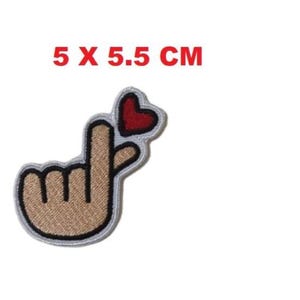 Op de afbeelding: Geborduurde patch met een handgebaar dat een hart vormt met een rood hart. De patch is ongeveer 5 cm bij 5,5 cm. De tekst "5 x 5.5 CM" wordt in het rood weergegeven.