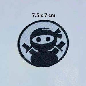 May include: Black and white embroidered iron-on patch of a ninja with two swords, 7.5 x 7 cm.