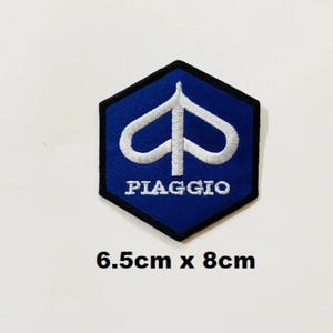Puede incluir: Un parche bordado azul y blanco con el logotipo de Piaggio. El logotipo es un símbolo estilizado blanco con la palabra "PIAGGIO" en letras blancas debajo. El parche mide 6,5 cm por 8 cm.