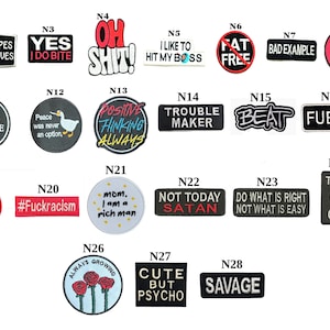 Könnte beinhalten: Eine Sammlung von Aufnähern mit verschiedenen Phrasen und Grafiken. Designs beinhalten "WTF", "Oh Shit", "Trouble Maker", "Eat Sleep Dance Repeat" und mehr. Die Aufnäher sind in verschiedenen Formen und Farben.