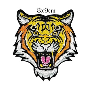 Könnte beinhalten: Gestickter Tigerkopf-Aufnäher, misst 8 x 9 cm. Der Aufnäher hat ein detailliertes Design mit orange, gelb, schwarz, weiß und rosa Farben. Der Tiger wird mit offenem Maul dargestellt, das seine Zähne und Zunge zeigt.