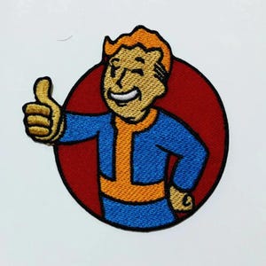 May include: An embroidered patch featuring a cartoon character giving a thumbs up. The character has orange hair, a blue jumpsuit, and a yellow undershirt. The character is smiling and is surrounded by a red circle.