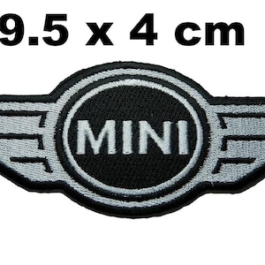 Puede incluir: Parche bordado con el logotipo de MINI, que mide 9,5 cm por 4 cm. El diseño presenta un logotipo circular negro con la palabra 'MINI' en blanco, flanqueado por alas plateadas. El parche es negro y plateado.