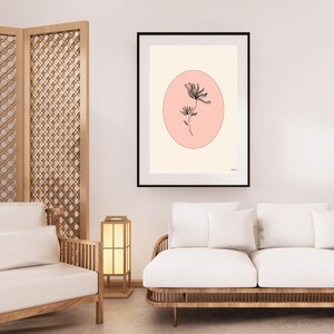 May include: A black and white line drawing of a flower inside a pink circle on a cream background. The image is framed in a black frame.