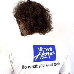 May include: White t-shirt featuring the Microsoft Home logo in a blue rectangle and the slogan "Do what you want to do." The shirt is made of a soft, comfortable material.