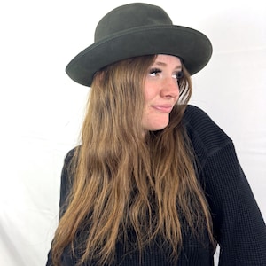 Peut inclure: Un chapeau fedora vert foncé avec une couronne arrondie et un large bord. Le chapeau est fait d'une matière douce et a un design classique et intemporel. Un accessoire élégant pour toute tenue.