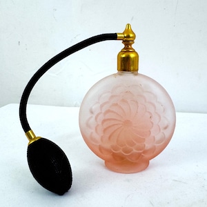 Atomizador de frasco de perfume vintage de vidrio rosa esmerilado con diseño de remolino floral.