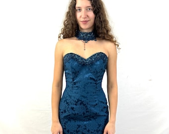 May include: A teal strapless dress with a lace bodice and a fitted silhouette. The dress has a floral pattern and is made of a satin-like fabric.